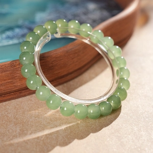Detailed view of translucent green agate beads on a clear acrylic stand with soft lighting