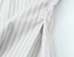 Détail de la texture rayée grise avec des boutons blancs sur une chemise ample