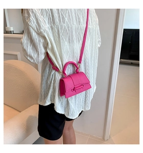 Detailed view of a hot pink pebbled leather mini crossbody bag with a gold metal clasp