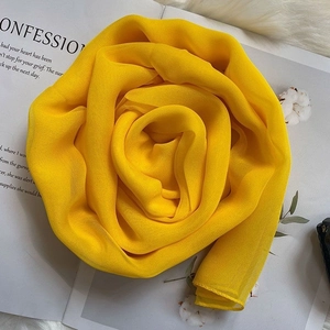 Bright yellow silk scarf folded into a rose shape on a luxury magazine background