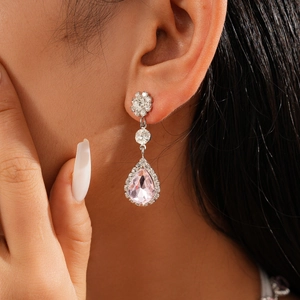 Close-up of pink teardrop earrings with halo diamonds on a model for elegant styling