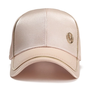 Detailed close-up of champagne satin baseball cap with gold M logo and metallic edging