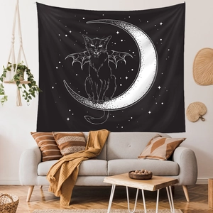 Detail of wall tapestry featuring black cat with wings on a moon crescent in a living room