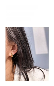 Detailed close-up of a twisted gold hoop earring with a polished metallic finish on a model