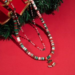 Detail of Christmas beaded necklace set with pearls and a small red golden bell pendant