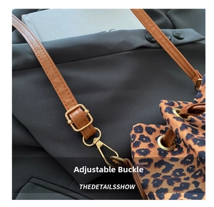 Detail of leopard print canvas bucket bag with adjustable brown leather shoulder strap
