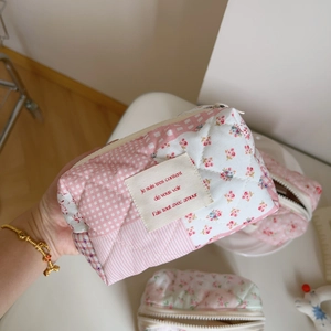 Detail of pink floral quilted cotton cosmetic bag with white label and zip closure