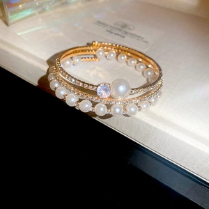 Macro shot of gold-plated layered bracelet with pearls and shimmering gemstones