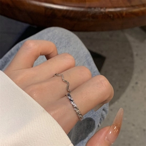 Detail of silver wavy band and twisted zircon ring set worn on a finger