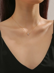 Close-up of minimalist gold titanium necklace with sparkling zircon pendant on model neck