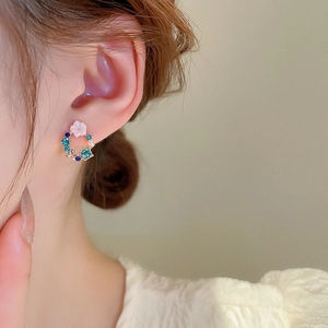Close-up of floral hoop earring with blue crystals and white pearl on ear