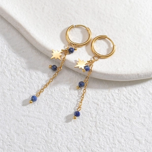 Detalle de pendientes en acero chapado oro 14K con dijes de estrella y cuentas azules