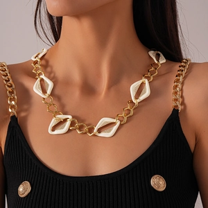 Gros plan d'un collier chaîne dorée avec losanges en émail blanc et cristaux sertis