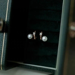 Detailed close-up of double-layer pearl earrings with zircon in a green velvet jewelry box