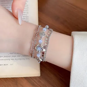 Vintage multilayer silver bracelet with light blue beads and floral charms on a book