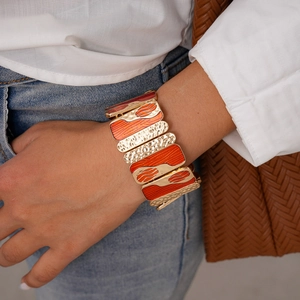 Detail of vintage metal stretch bracelet with orange enamel and hammered texture sections