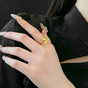 Close-up of a model wearing a gold floral steel ring with a matte finish design