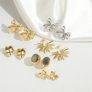 Detailed collection of vintage bow and heart earrings on a soft white satin fabric