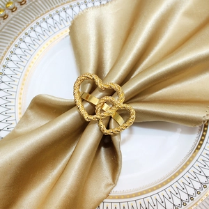 Detailed close-up of golden interlocking hearts napkin ring with fine woven metal texture