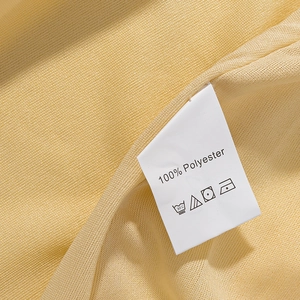 Detailed close-up of yellow knit dress fabric with a 100% polyester material care label