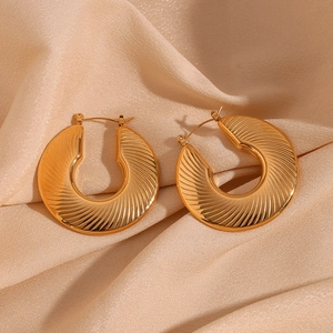 Detailed close-up of 18K gold plated C-shape earrings with radial spiral texture on silk