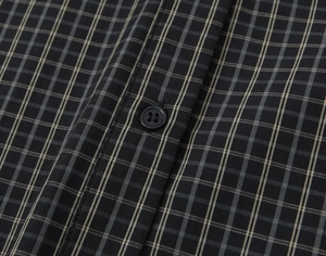 Close-up of black and yellow plaid fabric with textured buttons on a casual cotton shirt