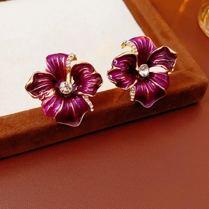 Detailed view of purple floral earrings with crystal center and golden trim finish