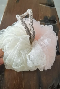 Detailed macro view of soft pink and white mesh bath sponge with a durable hanging rope