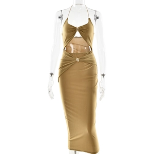 Detail of khaki halter maxi dress featuring waist cut-out and knot design on plain background