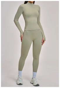 Detail of light olive yoga top featuring thumbhole cuffs and seamless zipper collar