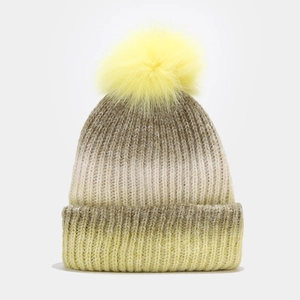 Détail du bonnet en maille avec dégradé jaune et gris et pompon en fourrure de renard