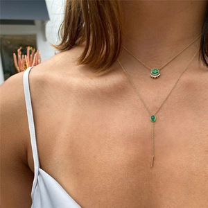 Double layered gold necklace with green oval zircon pendant and sunburst charm