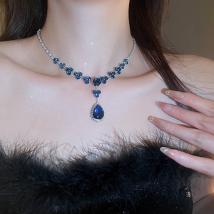 Detail of silver necklace with deep blue heart gemstone and pear-shaped drop pendant