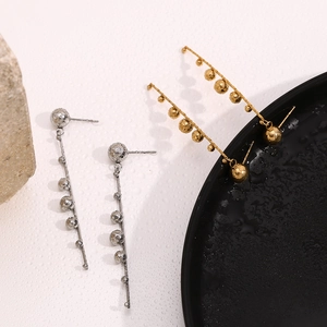 Detail of gold and silver linear drop earrings with multiple bead accents on stone decor