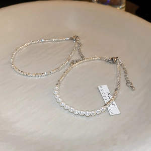 Detail of silver beaded bracelets with pearls and irregular silver nuggets on ceramic tray