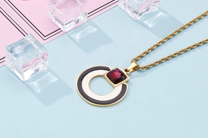 Macro shot of gold circle pendant with red gemstone on blue and pink background