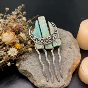 Close-up of silver crescent moon hair comb with turquoise stones on a natural rock