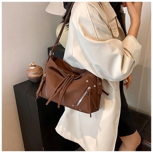 Dettaglio borsa a tracolla marrone con nappe e cerniere vintage indossata dalla modella