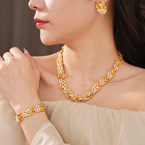 Detail of leaf-shaped gold finish jewelry set with pearls on a professional model