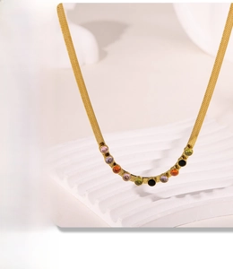 Macro detail of gold snake chain necklace featuring colorful round zircon stones