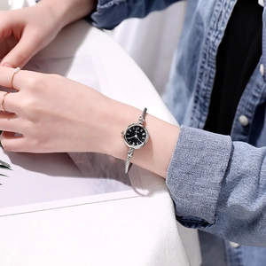 Detail of silver bangle watch featuring a black dial and twisted metal rope band on wrist