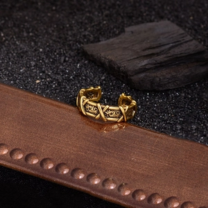 Bague dorée vintage croisée avec motifs floraux et poinçon S925 sur fond de sable noir
