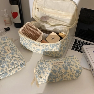 Three-piece quilted blue floral toiletry bag set with the jolly house label on a white desk