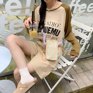 Detailed view of checkered mini crossbody bag with purple strap and brand woven label