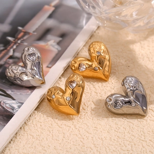 Detail of heart-shaped gold and silver earrings with star embossing and zircon stones