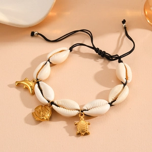Detail of shell beaded bracelet with golden turtle and dolphin charms on woven cord