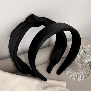 Detail of black fabric headbands with knot design and subtle polka dot texture
