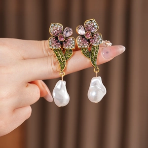 Gros plan de boucles d'oreilles vintage fleurs, strass mauves et perles baroques