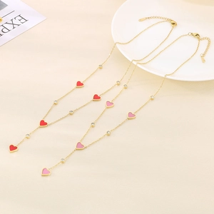 Detail view of gold heart necklace with red and pink enamel pendants and zircon accents