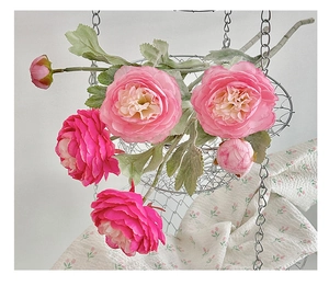 Close-up of pink artificial Persian Buttercup flowers in a hanging metal wire basket